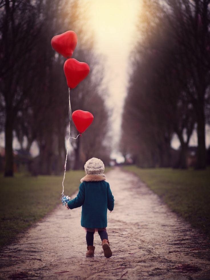 menininho na estrada segurando balões em forma de corações